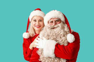 Happy Santa Claus and beautiful mature woman in Christmas hats on blue background