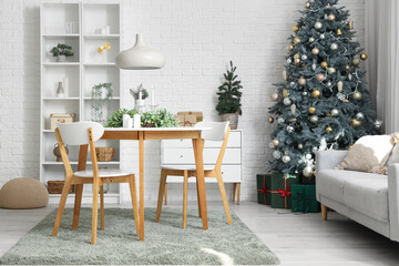 Stylish interior of light living room with mistletoe wreath and burning candles on table
