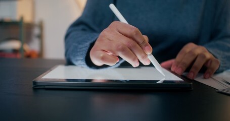A woman draws on a graphics tablet using a stylus, sitting at her desk in the office, close-up of...