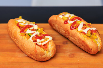 Two hot dogs with mustard and ketchup on a wooden table