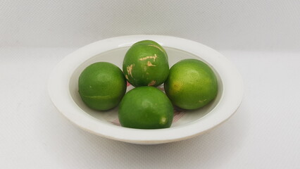 Green colored lemons lying in a plastic container 