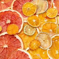Vibrant close-up of assorted dried citrus fruit slices including grapefruit, orange, and lime in a...