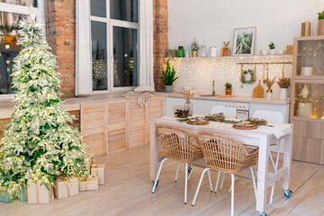 Christmas decor in the kitchen. A Christmas tree next to the festive table.