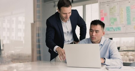 Two enthusiastic multiethnic businessmen celebrate closing business deal after receiving confirmation or updates via email or business news on laptop, relish joint success, sales growth, huge profit
