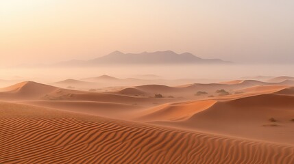 A foggy desert scene at dusk, with the last light of the day casting a soft glow over the mist-covered dunes