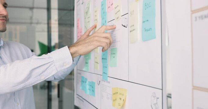 Close up of focused Hispanic office employee review information on sticky-notes, read priority or category, analyzing written data, prioritize post-it notes based on urgency, importance and deadlines