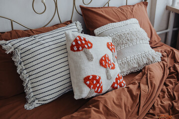 Cozy bedroom decor featuring patterned cushions on a warm-toned bedspread