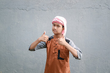 A Muslim man wearing a cap and scarf is giving a thumbs-up as a sign of approval.