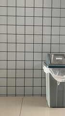 white checkered walls, with a trash can in the corner
