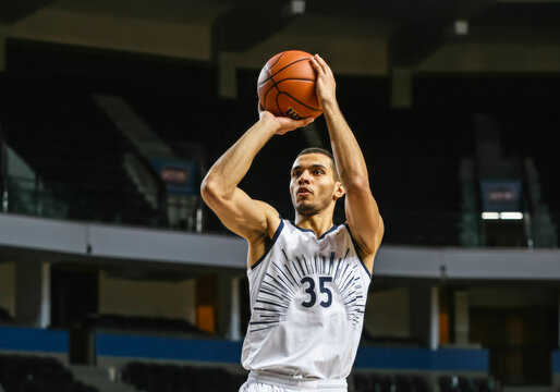 Professional basketball player shooting in empty arena