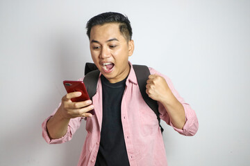 Surprised young Asian man student in casual clothes backpack holding mobile phone and looking aside empty space for advert isolated on white background. high school university college concept