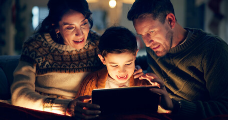 Fototapeta premium Tablet, relax and child with parents in home watching movie, film or show online for entertainment. Happy, light and kid on sofa with mother and father streaming video on digital technology at night.