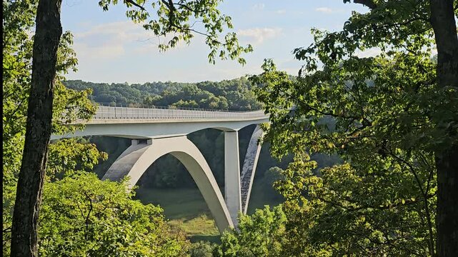 Natchez Trace Parkway bridge framed by trees. Constructed in 1994, the 1,572-foot long bridge spans across Birdsong Hollow approximately 155 feet above the valley. -Zoom in