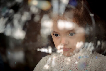 thoughtful little girl seeing through a globe