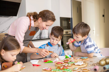 Fototapeta premium Happy family mother and children in aprons making Christmas cookies together while cooking