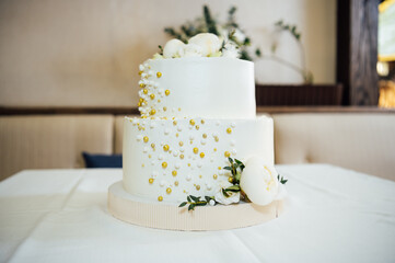 A beautiful wedding cake stands on a table in the sun