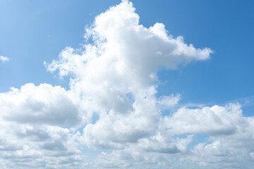 Fluffy white clouds drift across a clear blue sky, painting a beautiful summer day