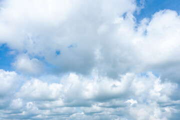 Fluffy cumulus clouds drift across a bright blue sky, painting a beautiful summer day