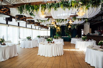 Luxurious restaurant. Luxurious interior, white tables, serving dishes and glasses for guests. Green decor