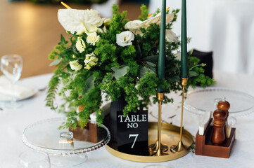 Luxurious restaurant. Luxurious interior, white tables, serving dishes and glasses for guests. Green decor