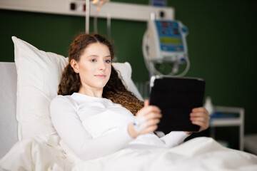 Happy delighted female patient with tablet in hands observes different photos from the past life...