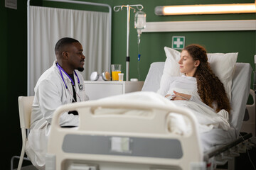 African doctor offering support to a patient by sitting nearby, expressing empathy and...
