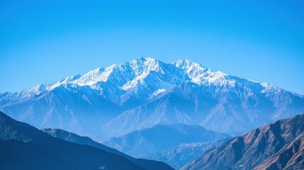 Obraz premium A majestic snow-capped mountain peak rises against a clear blue sky.