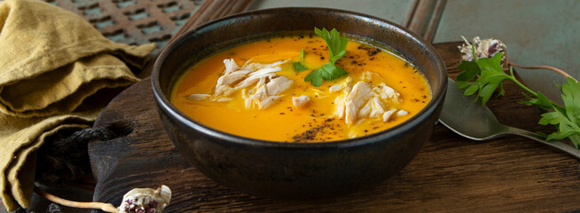 bowl of carrot cream soup with chicken on a  table