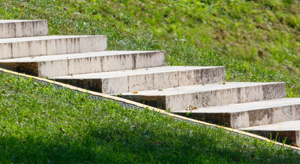 A set of concrete steps leading up to a grassy hill