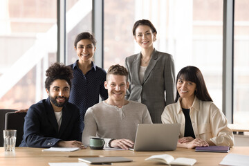Happy diverse business startup team office portrait. Happy confident multiethnic office workers looking at camera, posing at workplace table, smiling, celebrating job success