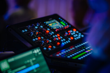 Obraz premium A close-up of an audio control panel with colorful illuminated buttons and knobs, capturing the details of a live event’s audio mixing equipment..