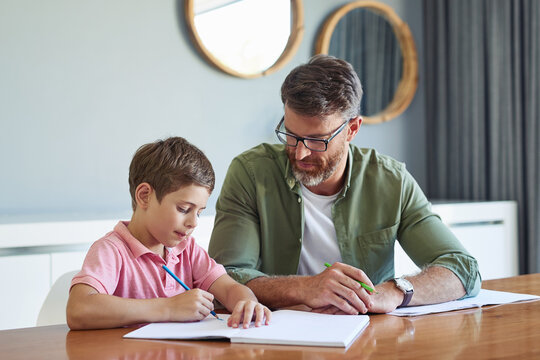 Education, homework or writing with father and son at dining room table of home for learning or study. Book, homeschool or scholarship with single parent man and student boy child in apartment