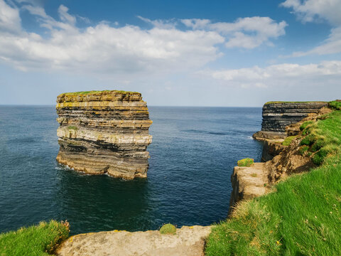 View on stunning Dun Briste sea stack in Downpatrick head, Ireland. Popular travel and tourist area with stunning scenery. Famous Irish landmark. Warm sunny day with blue cloudy sky.