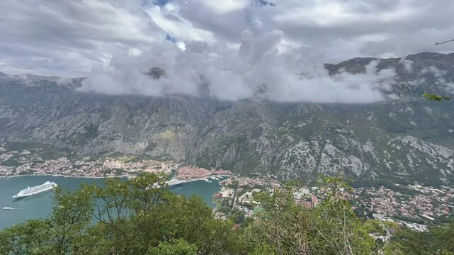Time-lapse video of Kotor cityscape and Bay from Vrmac mountain viewpoint with passing clouds over the scenic landscape