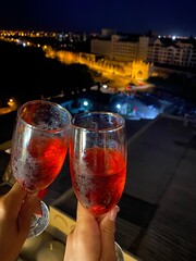 Romantic Rooftop Toast with Red Drinks Overlooking City Lights at Night