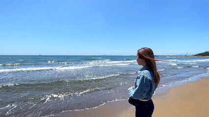 秋の晴れた青空と海辺を望む一人の女性