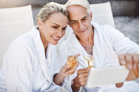Senior couple, selfie and champagne by swimming pool, toast and love at luxury resort on vacation. Mature man, woman and memory by water for celebration, drinks and cheers with wine glass in Greece