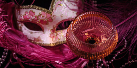 Masquerade ball holiday background. Glass of rose champagne, Venetian carnival mask and feathers on...