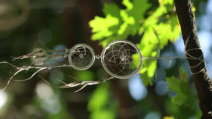 Decorative dream catcher handing on a tree branch. Vertical 4K footage - Powered by Adobe
