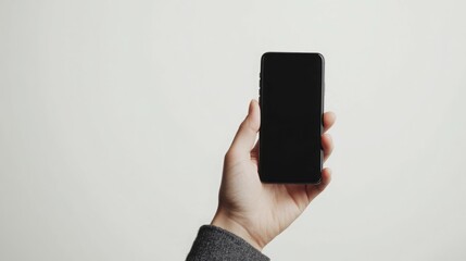 A hand holding a black smartphone with a blank screen.