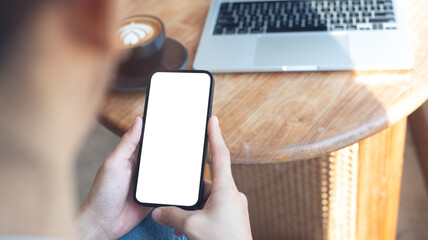 Cell phone white screen mockup, Woman hand holding mobile phone with blank screen while working at coffee shop. Business woman using smartphone, mockup for social media advertisement