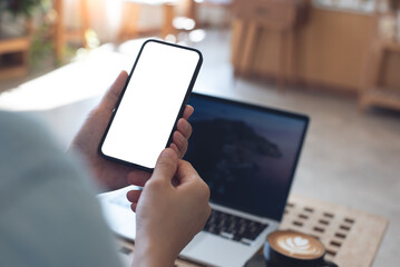 Cell phone white screen mockup, Woman hand holding mobile phone with blank screen while working at coffee shop. Business woman using smartphone, mockup for display mobile app interface design