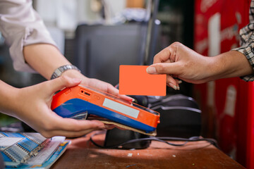 A customer is making a contactless payment transaction using an orange card at the store