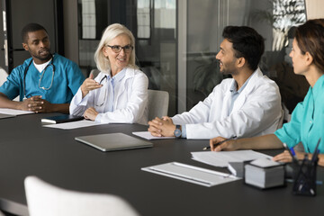 Experienced senior female professor of medicine clinical specialist lead multiethnic doctors group training workshop practicum at modern clinic. Friendly medic team listen to mature leader on seminar - Powered by Adobe