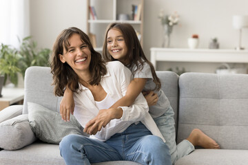 Sweet family moments. Happy laughing young mama little junior schoolgirl daughter play funny active...
