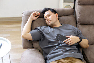Tired Asian Man Sleep on Sofa While Watching TV