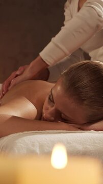 Woman is getting massage treatment from the therapist. Massaging procedure in spa. Healthcare, relaxation, rejuvenation and wellness concept.