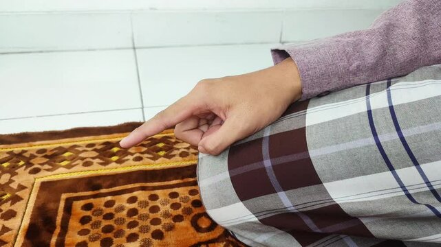 Muslim man pointing his index finger while praying at the final tahiyat