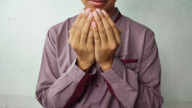 Muslim man wearing red koko shirt raises his hands and prays until finished with white background