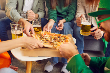 Closeup photo of young people friends men and women celebrating Saint Patrick's Day eating pizza...